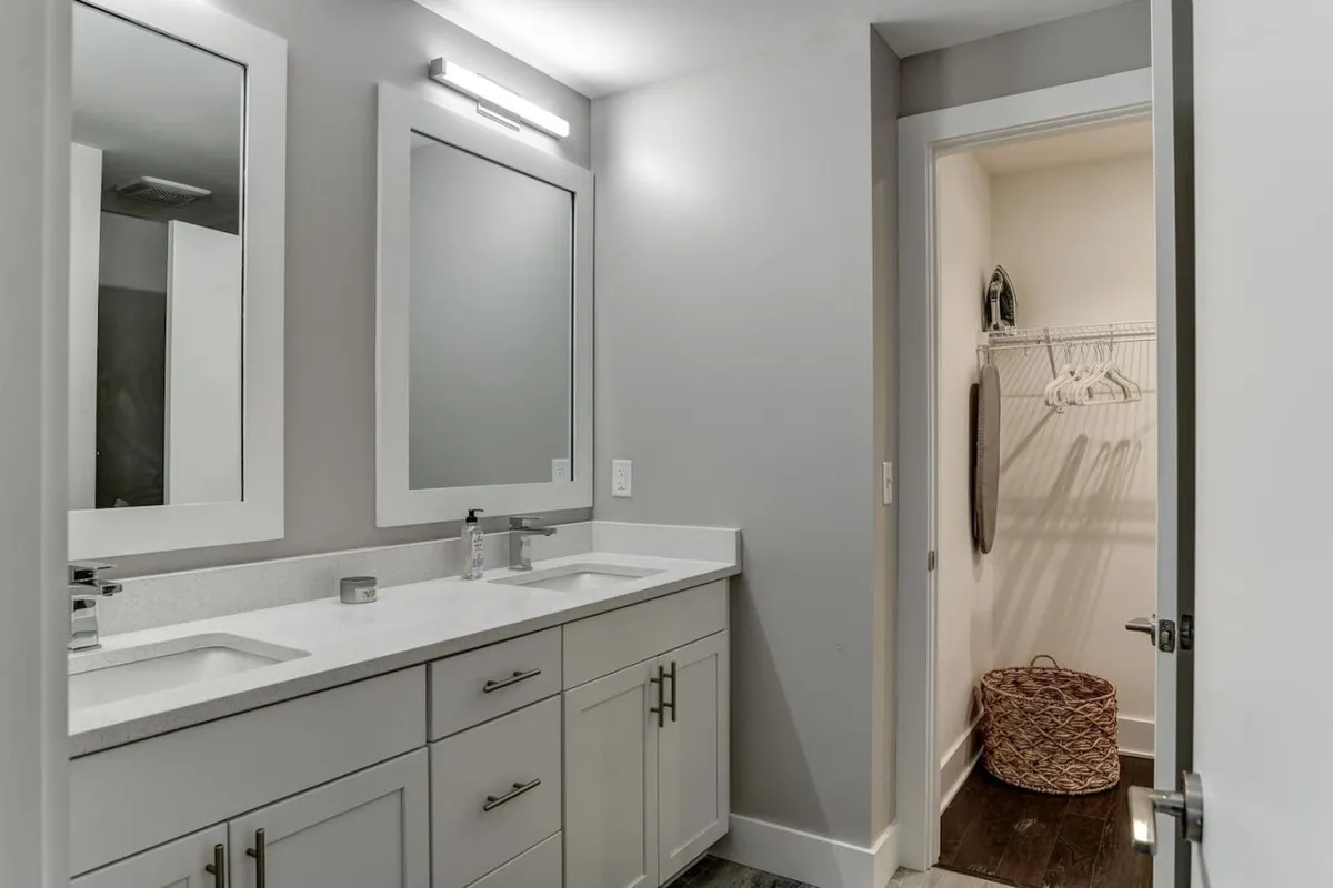 A modern bathroom with double vanity sinks, stylish mirrors, and contemporary light fixtures. The fresh and inviting space is ideal for self-care routines and shared morning preparations.