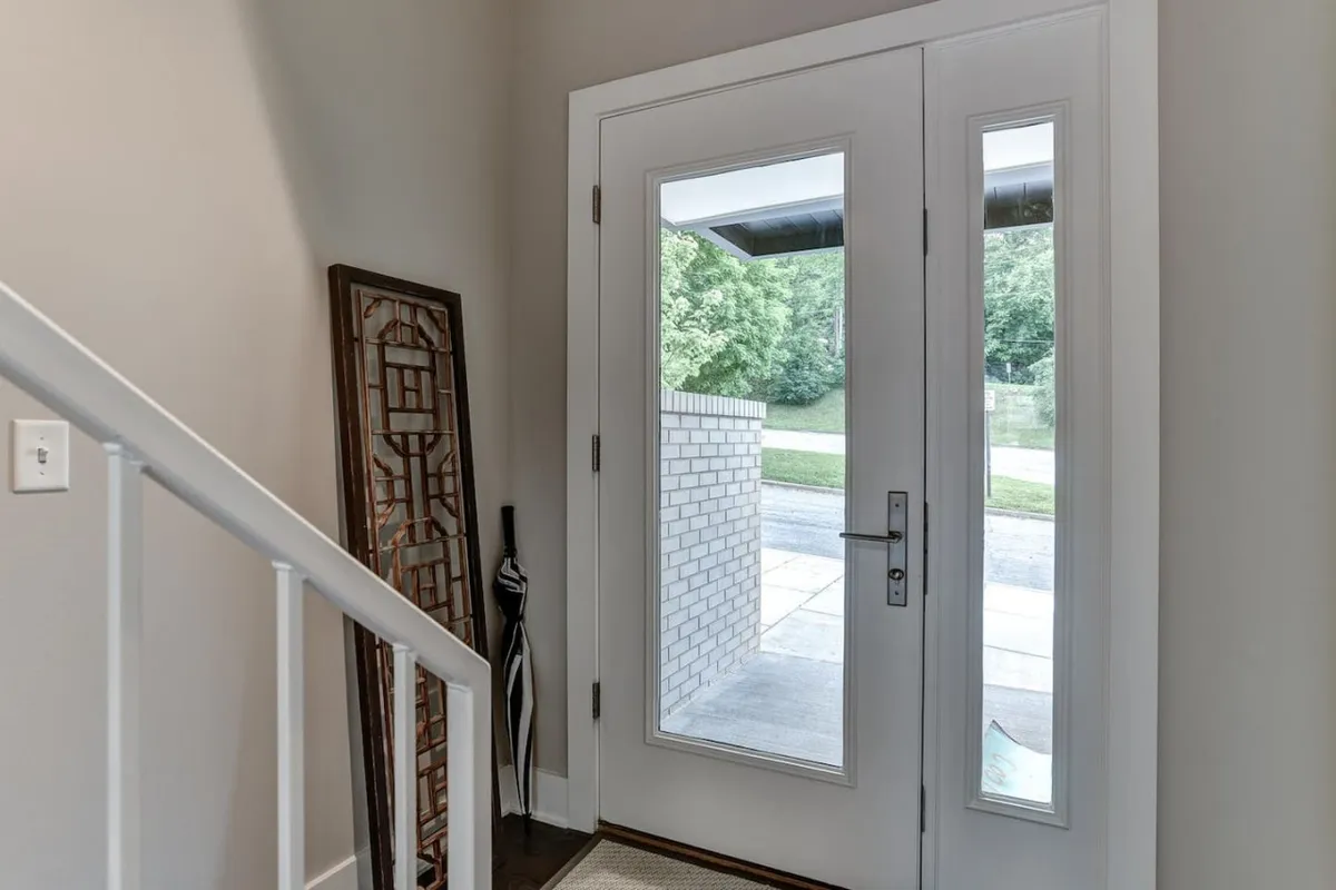 This image captures the home's inviting entryway, featuring a stylish front door, decorative panel, and an umbrella stand. It gives a sense of the warm welcome and thoughtful transition from outside to inside.