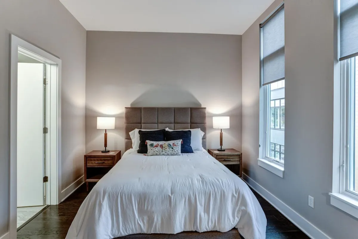 A calming bedroom scene with a plush bed, elegant headboard, and nightstands with softly glowing lamps. Decorative pillows and gentle lighting contribute to a cozy and restful atmosphere.